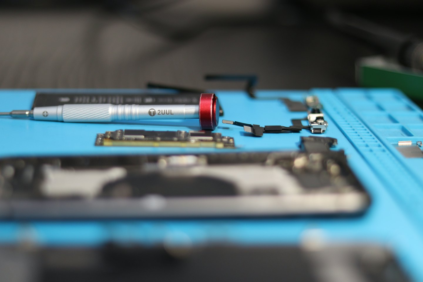 Präzisionsschraubendreher auf einer blauen Matte mit Elektronikteilen.